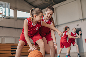 Two school-aged girls playing basketball