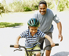Son biking with father looking on
