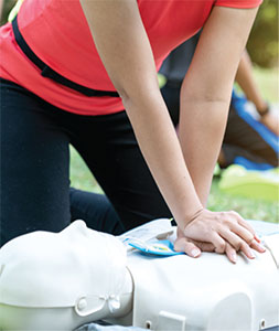 A woman practices CPR on a dummy.
