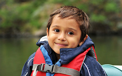 Child wearing a life jacket in a boat.