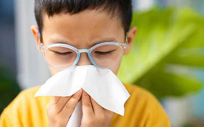 A boy in glasses blows his nose