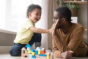 A father plays with a toddler.