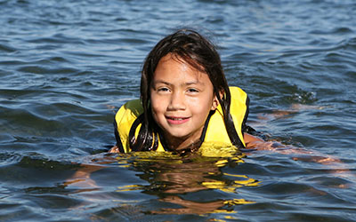 A girl wearing a life vest swimming