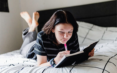 A teen on their bed with a journal