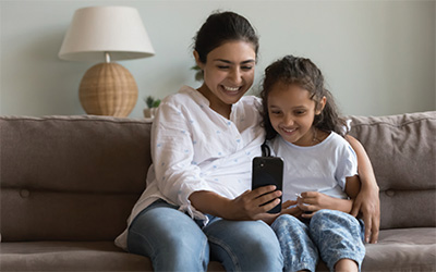 A mother and daughter look at a phone screen