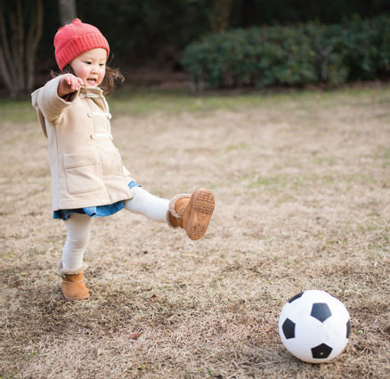 A young girl kicks a soccer ball