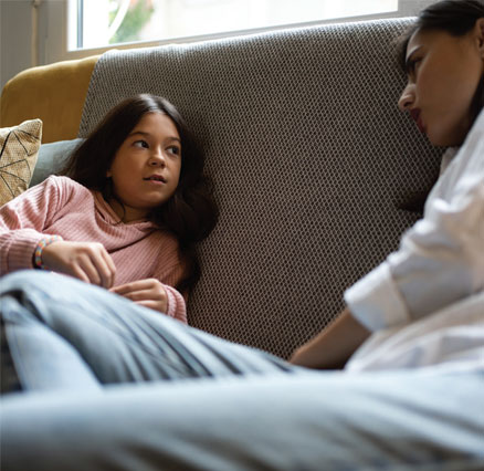 A girl talks to her mother on a couch