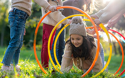 A girl crawls through a hoop tunnel