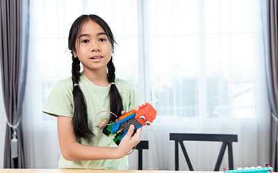 A girl holds a LEGO model