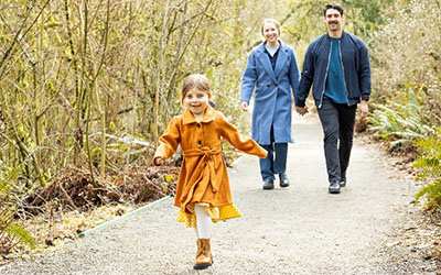 A young girl runs ahead of her parents on an outdoor trail