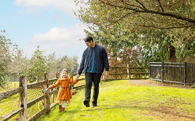 A father and daughter hold hands in a field
