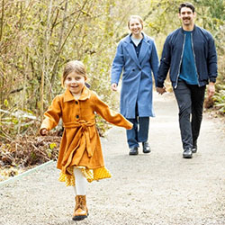 A young girl runs ahead of her parents on an outdoor path