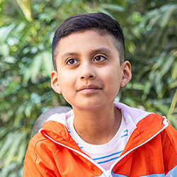 A boy sits in front of Seattle Children's Hospital