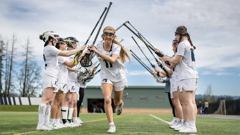 A teen lacrosse player run past her teammates