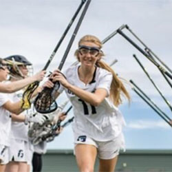 A teen lacrosse player run past her teammates