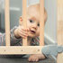 Baby looking out from behind the slats of a crib