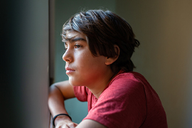 A teen looks out a window