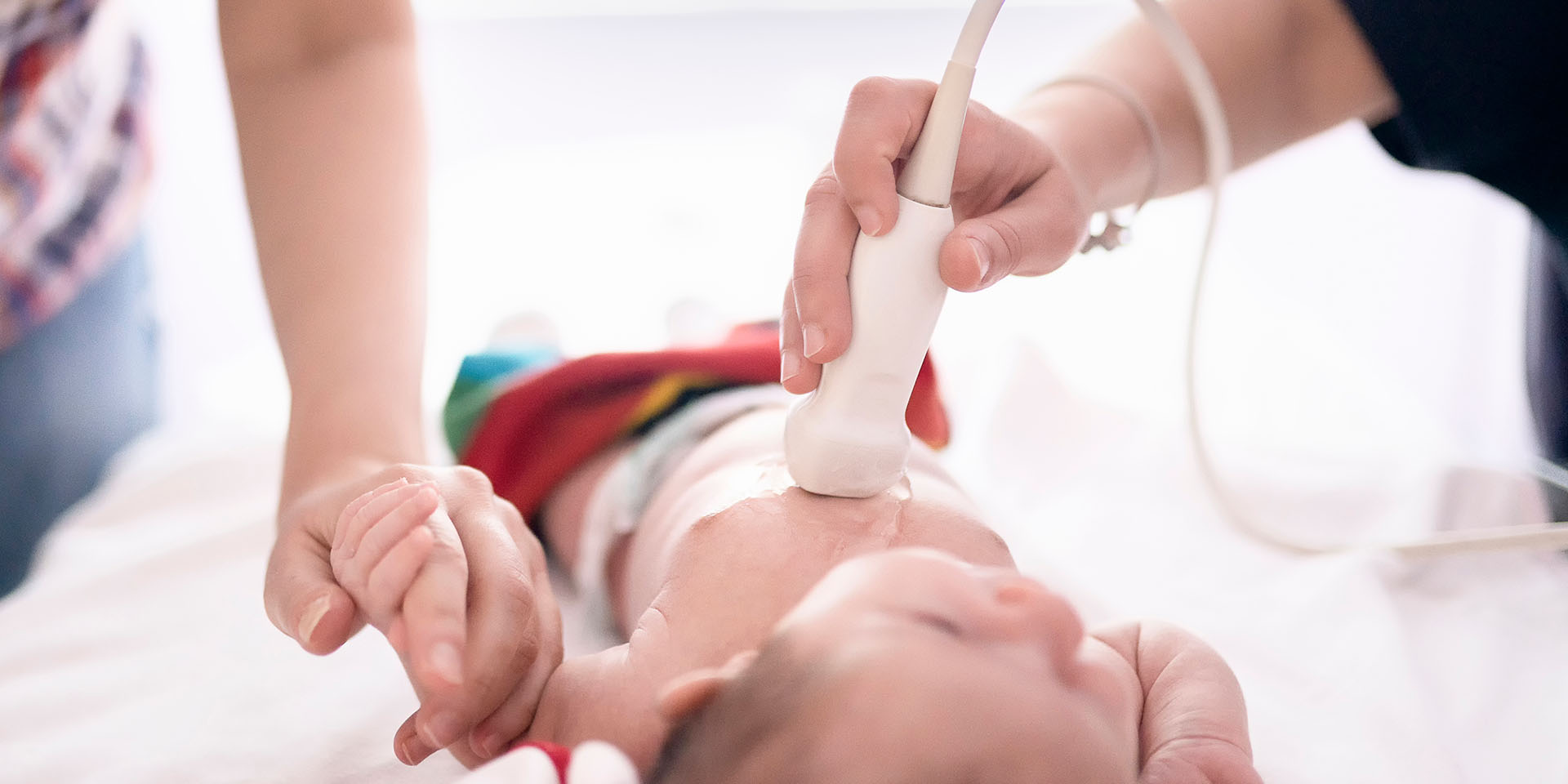 A provider performing an ultrasound on a newborn