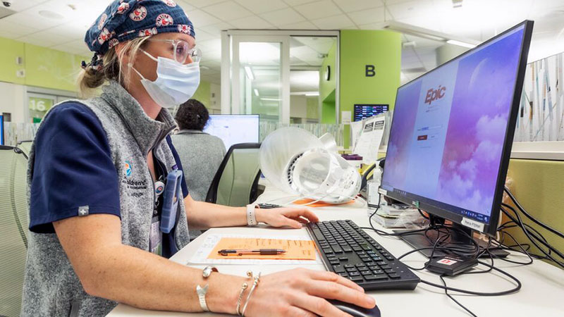 A Seattle Children's employee reviews information on a computer