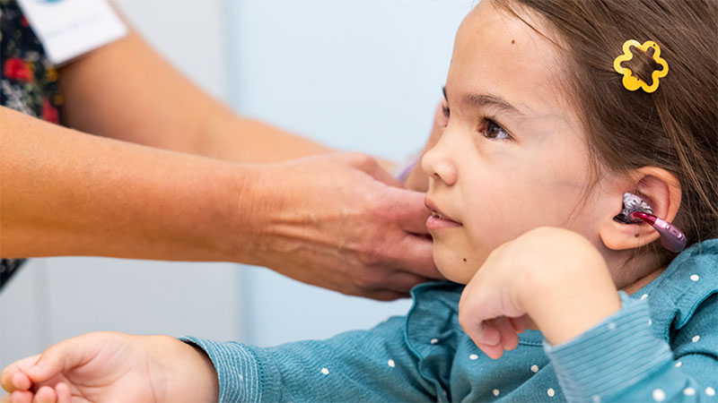 A girl has her hearing aid adjusted