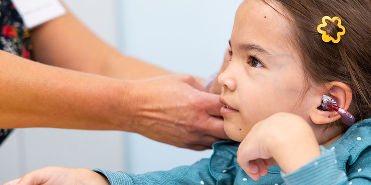 A girl has her hearing aid adjusted