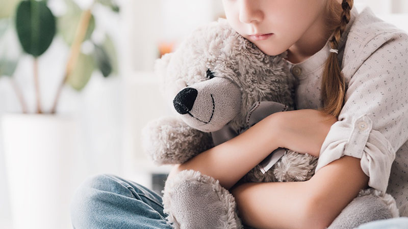 A girl holds a teddy bear