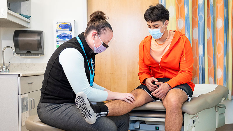 A nurse examines a teen boy's knee at Seattle Children's