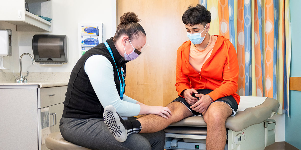 A nurse examines a teen boy's knee at Seattle Children's