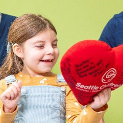 A girl holds a heart-shaped pillow