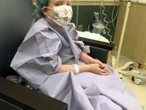A girl in a hospital gown and face mask at Seattle Children's