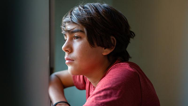 Teen boy looking out a window
