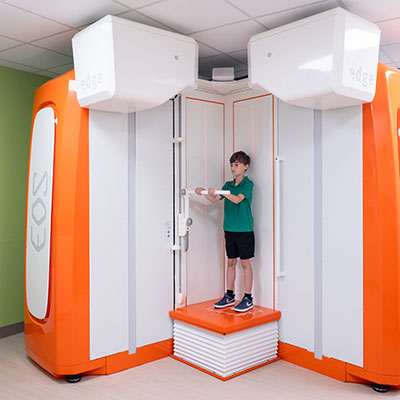 A boy stands in an EOS machine