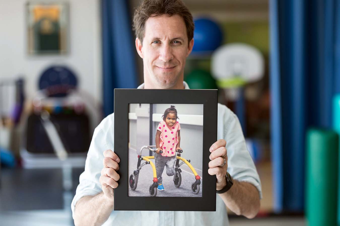 A man holds a framed picture of a Seattle Children's patient.