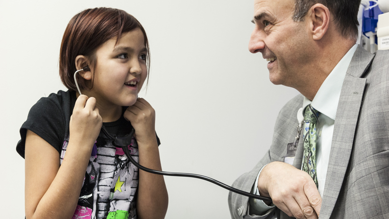 Zoe uses a stethoscope to listen to Dr. Simon's heart