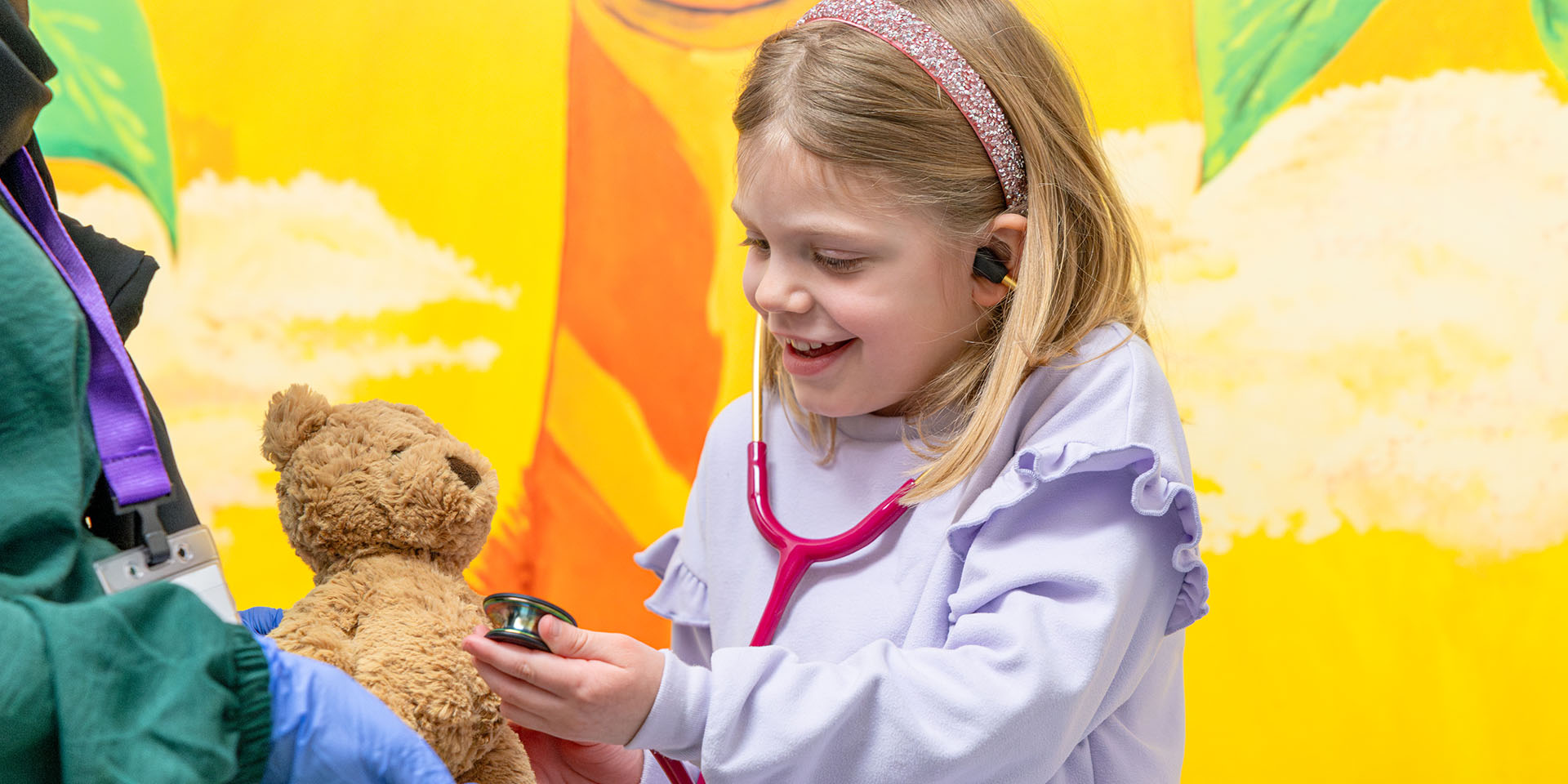 Young girl uses stethoscope to check teddy bear at Richmond Pediatrics.