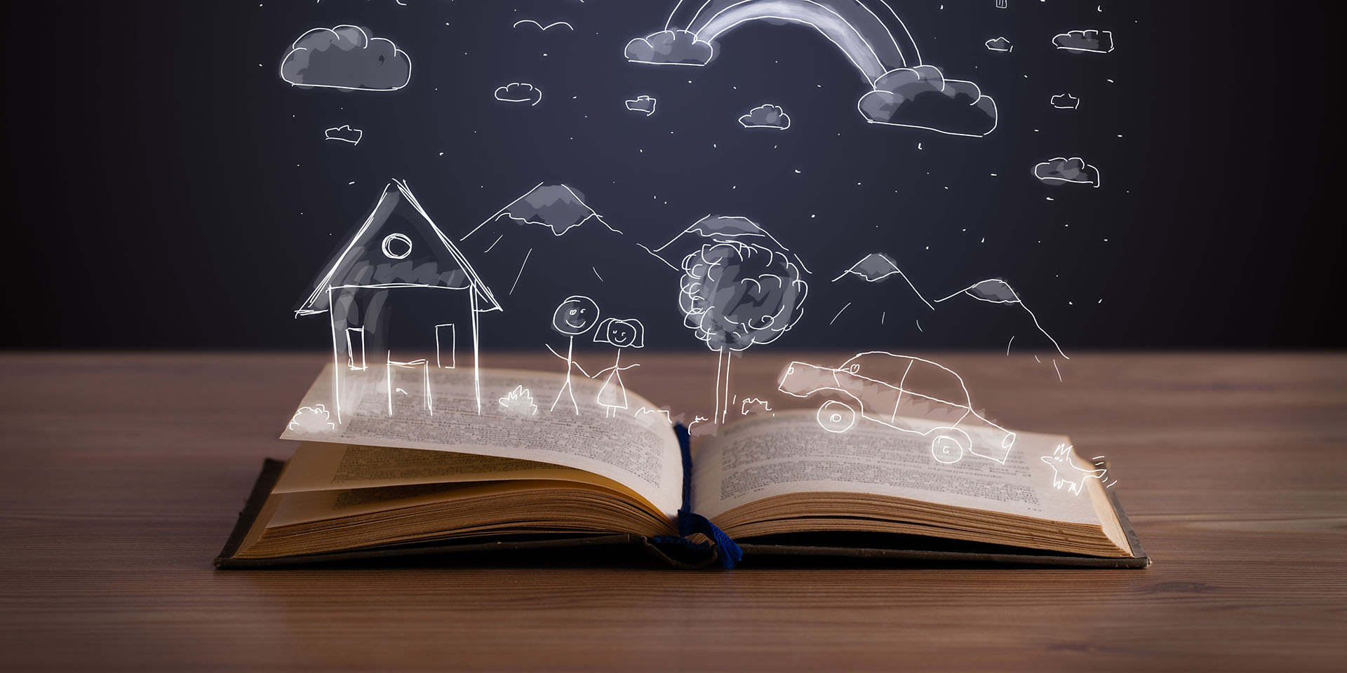 An open book sits on a table. A scene including a house, trees, mountain and rainbow, drawn in chalk, emerges from the pages.