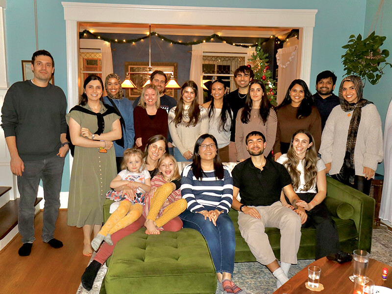 Lab members and friends in a living room decorated for the holidays