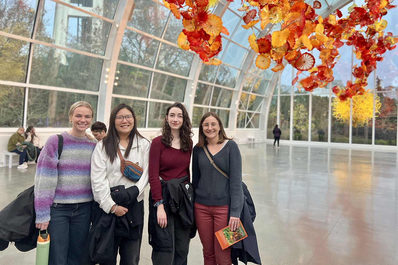 Four women stand in front of glass scultures