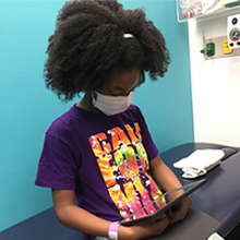 A girls looks at a tablet computer in a hospital