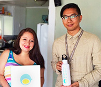 A woman and a man hold objects and pose for the camera