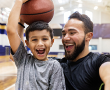 Child and an adult smile holding a basketball