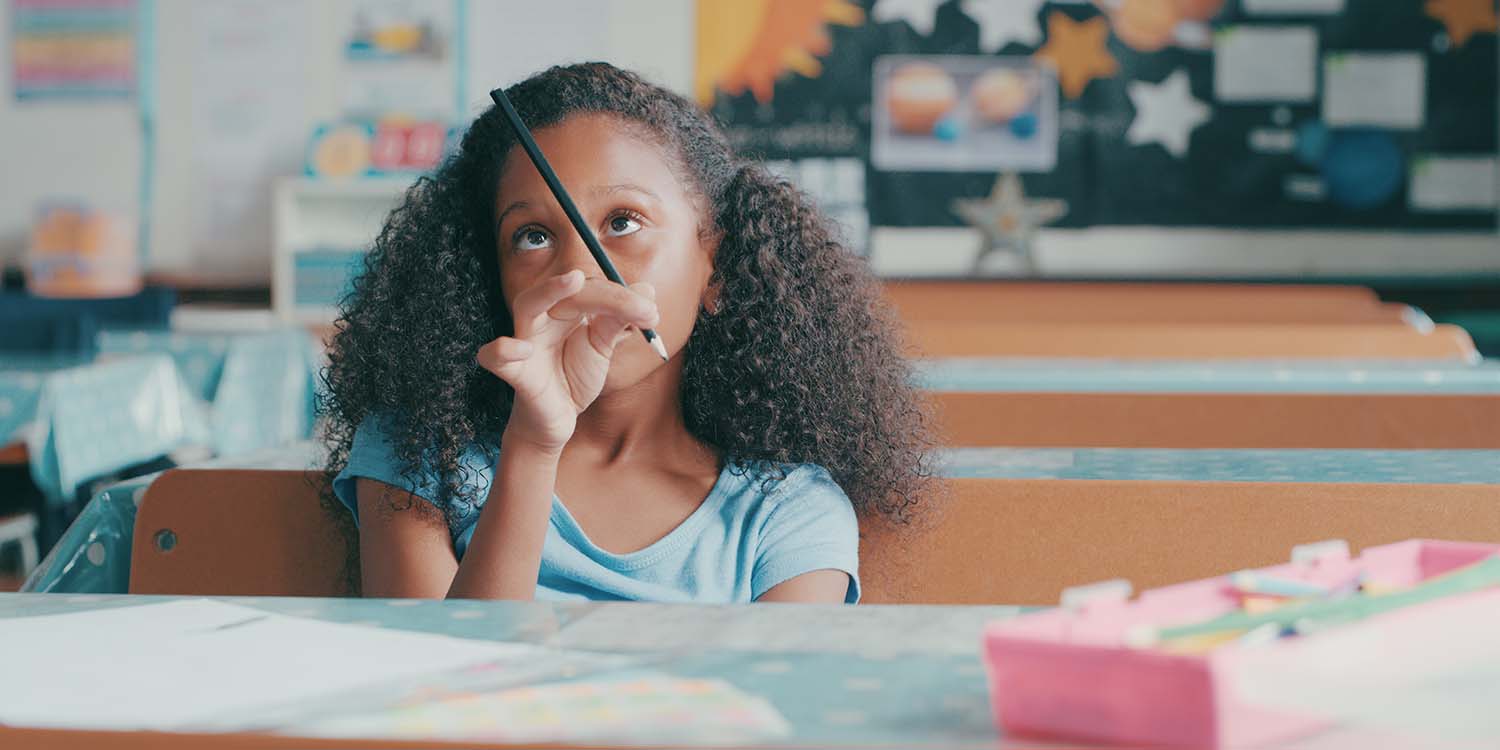 A girl stares at the end of her pencil.