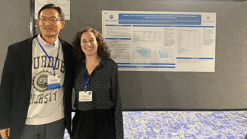 A male researcher and a female researcher standing next to a conference poster