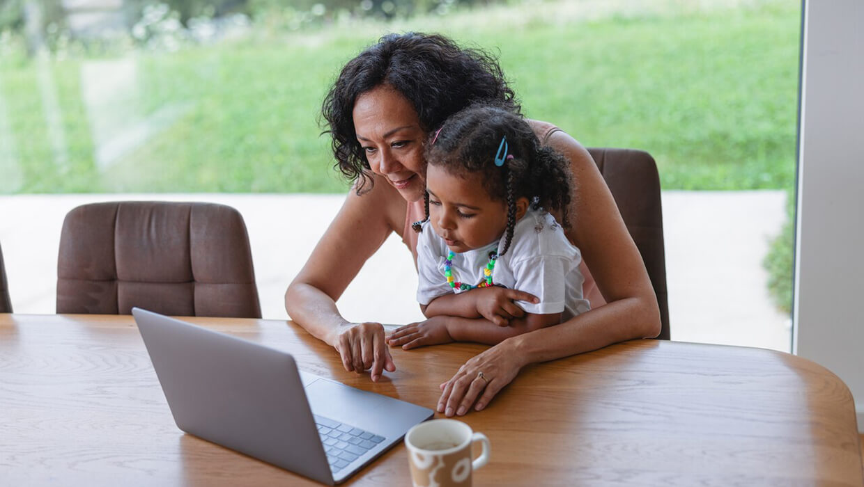 A mother and daughter look at a computer