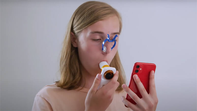 A woman using an inhaler and app
