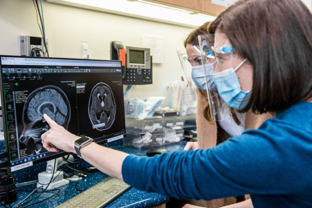 Two researchers look a an MRI of a brain on a computer screen