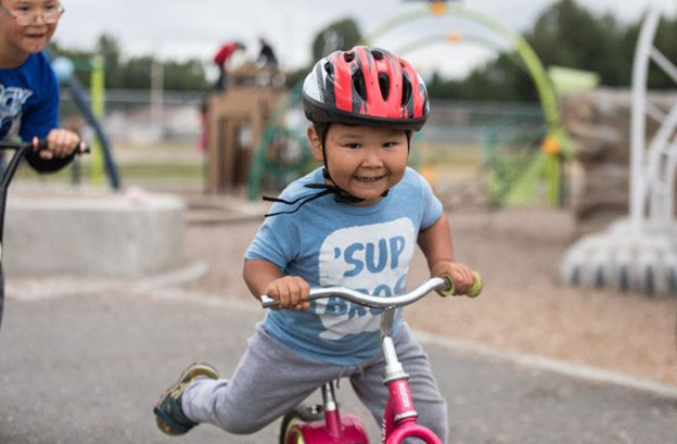 A boy wearing a helmet rides a bike