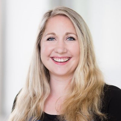 Dr. Meghan McGarry, woman with blonde hair and blue top stands, smiles for camera.