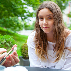 Parent with cell phone at table with teen girl