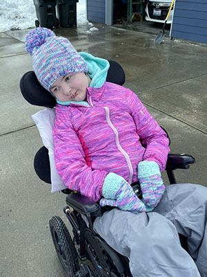 A girl in winter gear sits in a wheelchair